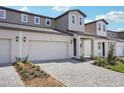 A townhome's exterior shows a two-car garage, stylish lighting, and a paved driveway with fresh landscaping at 1801 Archer Dr, Minneola, FL 34715
