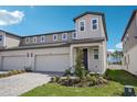 Exterior elevation showcasing a modern two-story townhome with a two-car garage and landscaped front yard at 1801 Archer Dr, Minneola, FL 34715