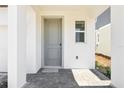 Inviting front door entrance featuring a tiled porch and white columns, with a gray door at 1812 Archer Dr, Minneola, FL 34715