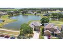Aerial view of a lakeside home with a lush green lawn and community at 2260 The Oaks Blvd, Kissimmee, FL 34746
