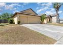Spacious driveway leading to a three-car garage, accented by lush landscaping and vibrant lawn at 2739 Village Pine Ter, Orlando, FL 32833