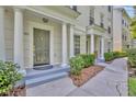 Covered townhouse entryway with classic pillars, trimmed hedges, and a gray entryway step at 312 Grand Bay Ln, Celebration, FL 34747