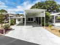 White home featuring a covered carport, mature landscaping, and bright blue skies at 367 Par Pines Blvd, Davenport, FL 33837