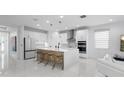 Modern, white kitchen featuring an island with seating, stainless steel appliances, and pendant lighting at 5511 Orange Orchard Dr, Winter Garden, FL 34787