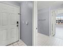Entryway featuring a white door with modern hardware and a glimpse into the tiled hallway and spacious living area at 5530 Metrowest Blvd # 309, Orlando, FL 32811