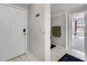 View of the foyer with a white door, tile floor, coat rack and view into the bedroom at 5566 Metrowest Blvd # 304, Orlando, FL 32811