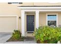 Close-up of the front entrance featuring a dark blue door, white pillars, and vibrant green bushes at 740 Simone Ct, Haines City, FL 33844