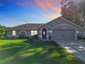 Charming one-story home with a well-manicured lawn and an attached two-car garage, enhanced by a twilight sky at 1072 Se 155Th St, Summerfield, FL 34491