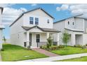 A charming two-story home boasts a welcoming front porch, complemented by lush green lawn at 11941 Bracco St, Winter Garden, FL 34787