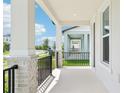 Covered porch features elegant columns, black metal railing, and a view of the neighborhood at 11941 Bracco St, Winter Garden, FL 34787