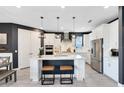 Bright kitchen with white cabinets, stainless steel appliances, a large island with seating, and modern pendant lighting at 13807 Tybee Beach Ln, Orlando, FL 32827