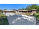 Exterior elevation highlighting the stone accents, covered porch, mature trees and driveway at 20 Lido Rd, Winter Springs, FL 32708