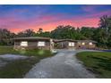 Exterior elevation of home showcasing stone accents and mature trees against a sunset backdrop at 20 Lido Rd, Winter Springs, FL 32708