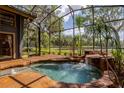 Relaxing spa pool featuring a rock waterfall and surrounding tropical plants in a screened-in enclosure at 3359 Scarlet Dr, Sanford, FL 32773