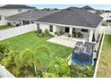Inviting backyard features a covered patio with dining and lounge furniture, a green lawn, and a play area at 62 Polermo Ave, St Cloud, FL 34771