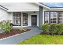 A welcoming front porch features black framed windows, gray brick accents, and professional landscaping at 7025 Hiawassee Oak Dr, Orlando, FL 32818