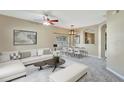 Spacious living room featuring neutral walls, carpet flooring, ceiling fan and an open dining area at 709 Strihal Loop, Oakland, FL 34787
