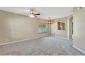 Spacious living room featuring neutral walls, carpet flooring, ceiling fan and an open dining area at 709 Strihal Loop, Oakland, FL 34787