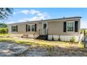 Charming single-story home with a front porch, neutral siding, black shutters, and mature plants by the front door at 8218 Pine Island Rd, Clermont, FL 34711
