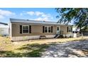 Charming single-story home with a front porch, neutral siding, and black shutters on a sunny day at 8218 Pine Island Rd, Clermont, FL 34711