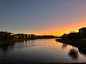 Scenic sunset view of a tranquil pond reflecting the warm colors of the sky, with houses lining the water's edge at 8405 Adalina Pl, Orlando, FL 32827