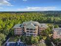 Wide aerial shot of the condo building surrounded by lush greenery and trees, with a parking area visible at 9061 Treasure Trove Ln # 403, Kissimmee, FL 34747