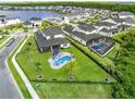 Aerial view of a backyard featuring a pool, spa, outdoor seating, and manicured lawn in a suburban neighborhood at 9877 Laurel Berry Dr, Orlando, FL 32827