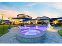 Inviting backyard with a uniquely shaped pool, connected hot tub, fountain feature and ample seating under the sunset at 9877 Laurel Berry Dr, Orlando, FL 32827