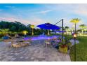 Relaxing backyard oasis featuring a custom pool, lounge seating, mature tropical landscaping, and paver decking at 9877 Laurel Berry Dr, Orlando, FL 32827