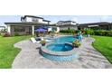 Resort-style backyard showcasing a sparkling pool, hot tub, and lush landscaping, creating a private oasis for relaxation and enjoyment at 9877 Laurel Berry Dr, Orlando, FL 32827