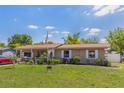 Charming single-story home featuring a lush lawn, lovely garden beds, and an American flag at 1219 Blue Spring Ct, Ocoee, FL 34761