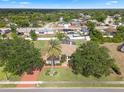 Aerial view of home with mature trees, screened-in lanai, and long decorative driveway at 1441 Olde Kensington Ln, Deltona, FL 32725