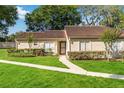 Single-story home with a well-kept lawn, trimmed hedges and brown roof at 262 W Sabal Palm Pl, Longwood, FL 32779