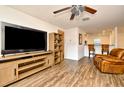 Cozy living area featuring wood flooring, a ceiling fan, a leather recliner and a large TV at 35734 Rose Moss Ave, Leesburg, FL 34788