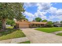 Traditional ranch-style home with an attached garage, driveway, and mature trees at 413 Sandy Hill Dr, Longwood, FL 32779