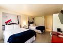 Bright hotel room with two beds, white linens, unique artwork, and hardwood floors at 5245 W Irlo Bronson Memorial Hwy # 151, Kissimmee, FL 34746
