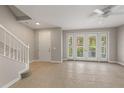 Bright living room featuring tile floors, staircase, and double doors leading to a balcony at 724 Greybull Run, Lake Mary, FL 32746