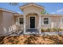 Close up of charming single-story home with a black front door, white shutters and shade trees at 1084 Doyle Rd, Deltona, FL 32725