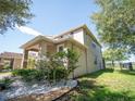 Side view of a two-story home featuring stone accents, lush landscaping, and a black metal fence in the backyard at 11742 Chateaubriand Ave, Orlando, FL 32836