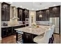 Gourmet kitchen features dark cabinetry, granite countertops, stainless steel appliances, and a large center island with seating at 14025 Hench Ln, Orlando, FL 32827
