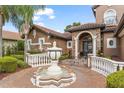 Close up of the front entrance with a decorative fountain, arched doorway, and meticulously maintained landscaping at 1450 Belfiore Way, Windermere, FL 34786