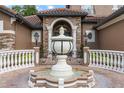 Grand home entrance featuring a custom fountain, arched entryway with columns, and a clay tile roof at 1450 Belfiore Way, Windermere, FL 34786