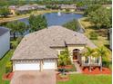 Stunning home showcasing a beautiful pond view, well-manicured landscaping, and an inviting two-car garage at 16313 Birchwood Way, Orlando, FL 32828