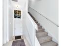 Bright, airy hallway featuring a staircase with white banister and a stylish accent window above the front door at 171 Mcleods Way, Winter Springs, FL 32708