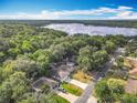 Aerial view of a neighborhood with lush green trees, single-story homes, and a serene lake in the distance at 185 Poinciana Ln, Deltona, FL 32738