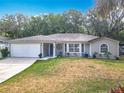 Single-story home featuring a well-manicured lawn, a two-car garage, and welcoming curb appeal at 185 Poinciana Ln, Deltona, FL 32738