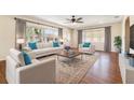 Sunlit living room featuring hardwood floors, comfortable seating, and large windows with bright curtains at 21529 Prince Albert Ct, Leesburg, FL 34748