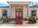 Elegant front entrance featuring double doors, columns, and decorative landscaping at 235 Hollingshead Loop, Davenport, FL 33896