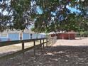 Exterior view showcasing a light blue house with a wooden fence and barn, shaded by trees at 25618 Fishermans Rd, Paisley, FL 32767