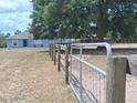 Property featuring a light blue house, wooden and metal fencing, set against a backdrop of lush greenery at 25618 Fishermans Rd, Paisley, FL 32767
